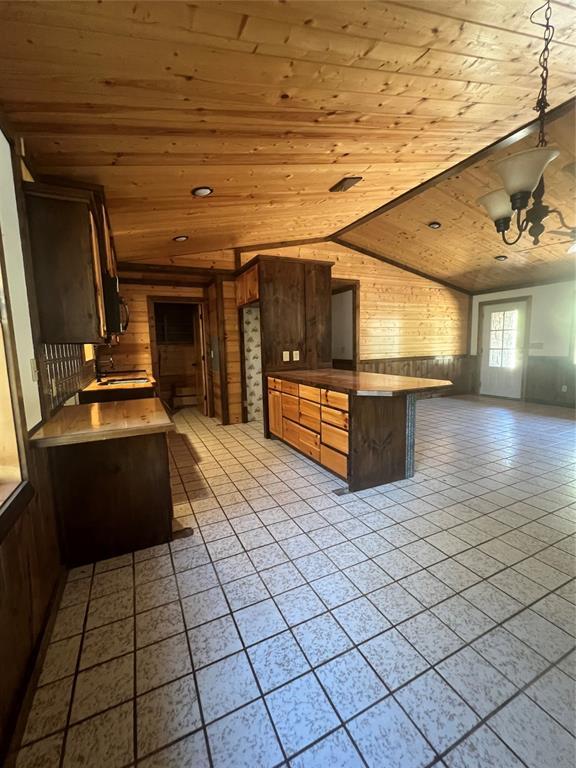 kitchen featuring wood ceiling, an inviting chandelier, vaulted ceiling, kitchen peninsula, and wood walls