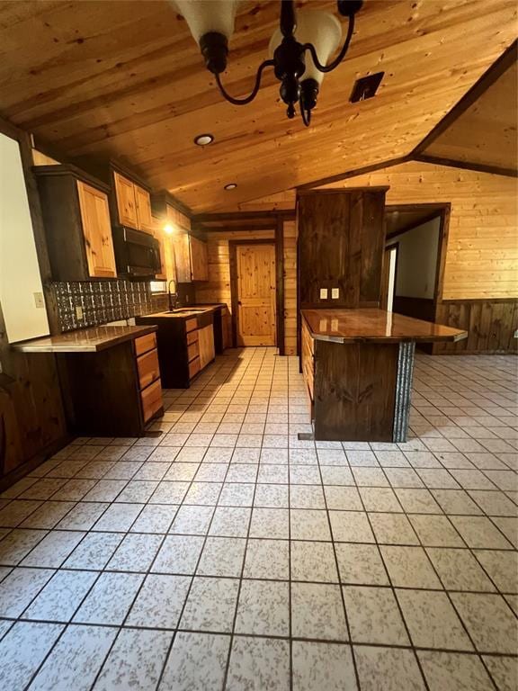 kitchen with sink, wood ceiling, a breakfast bar area, vaulted ceiling, and wood walls