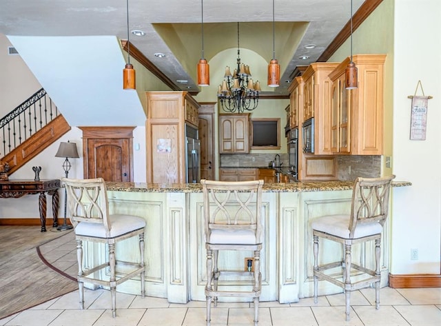 kitchen featuring light stone countertops, kitchen peninsula, hanging light fixtures, and a breakfast bar area