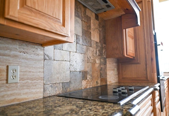 kitchen with decorative backsplash, black electric stovetop, and range hood