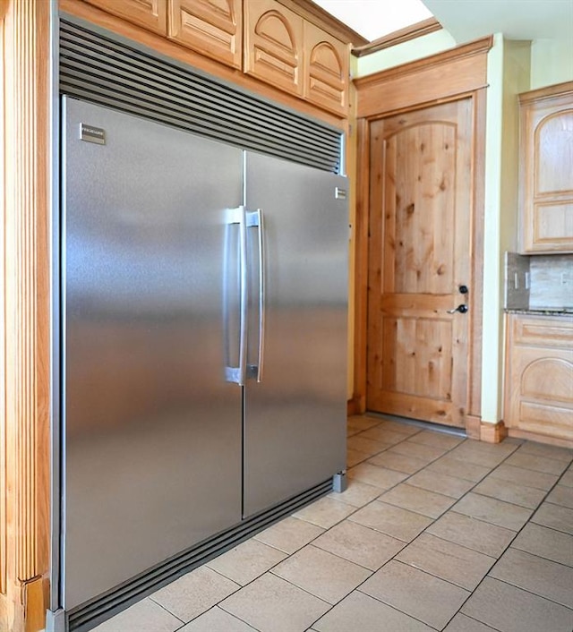 kitchen with light tile patterned flooring, stainless steel built in refrigerator, and light brown cabinetry