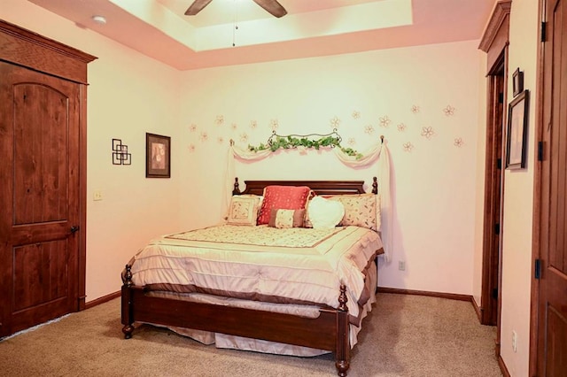 carpeted bedroom featuring ceiling fan and a tray ceiling