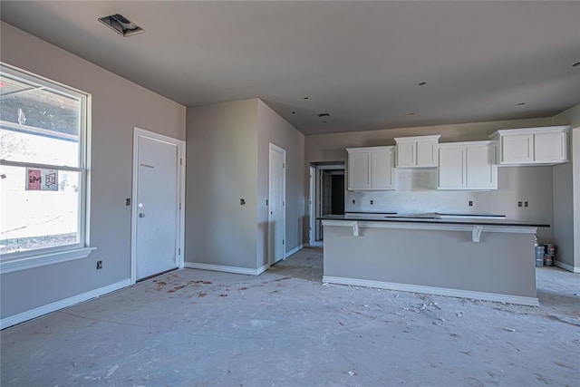 kitchen with a kitchen breakfast bar, decorative backsplash, a center island, and white cabinets