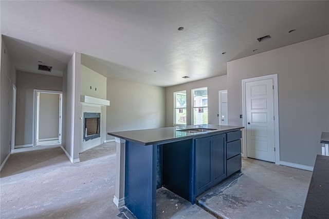 kitchen featuring blue cabinetry, sink, and an island with sink