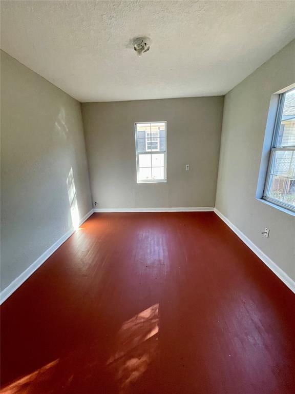 unfurnished room featuring hardwood / wood-style flooring, a textured ceiling, and a wealth of natural light