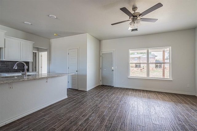 kitchen featuring dark hardwood / wood-style flooring, tasteful backsplash, light stone counters, sink, and white cabinets