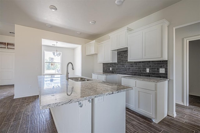 kitchen with white cabinets, a center island with sink, sink, tasteful backsplash, and dark hardwood / wood-style flooring