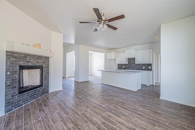 kitchen featuring backsplash, an island with sink, white cabinets, and dark wood-type flooring