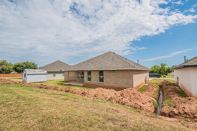 rear view of property with a shed, a patio area, and a lawn