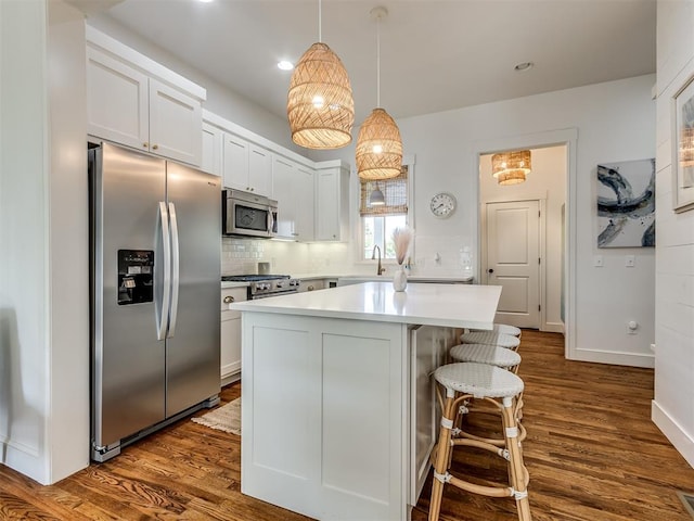 kitchen with white cabinets, stainless steel appliances, dark hardwood / wood-style floors, and hanging light fixtures