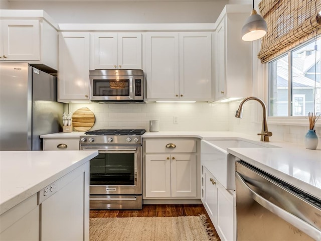 kitchen featuring backsplash, white cabinetry, hanging light fixtures, and appliances with stainless steel finishes