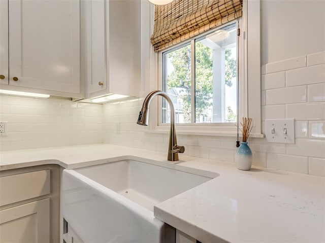 details featuring white cabinets, sink, and backsplash