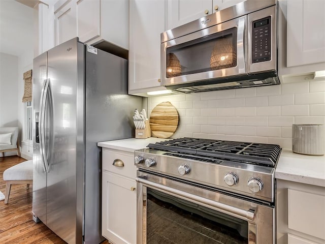 kitchen featuring decorative backsplash, white cabinets, light hardwood / wood-style floors, and appliances with stainless steel finishes