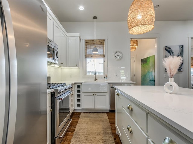 kitchen featuring white cabinetry, sink, dark wood-type flooring, pendant lighting, and appliances with stainless steel finishes