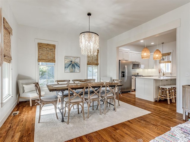 dining space with a chandelier, dark hardwood / wood-style flooring, and sink