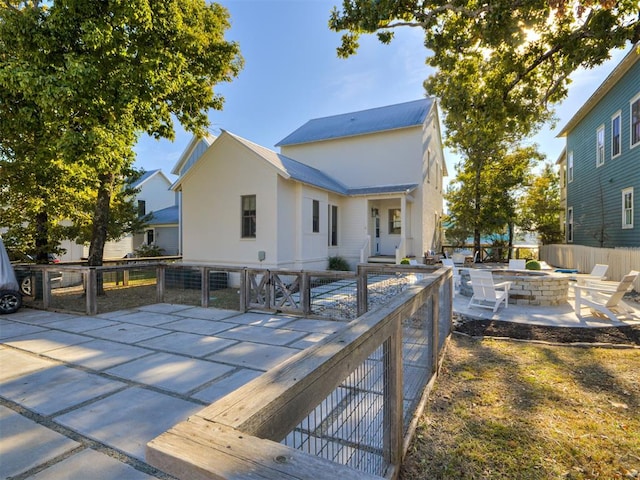 rear view of house with a fire pit and a patio area