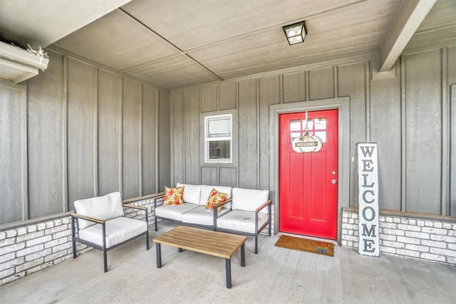 view of exterior entry with board and batten siding and an outdoor living space