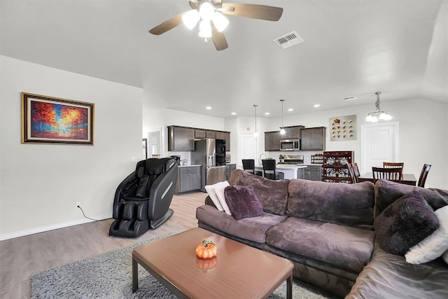 living area featuring recessed lighting, ceiling fan with notable chandelier, visible vents, baseboards, and light wood-type flooring