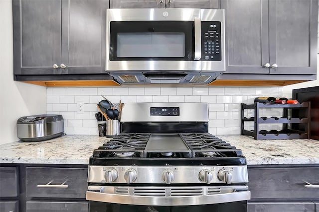 kitchen featuring light stone countertops, stainless steel appliances, and decorative backsplash