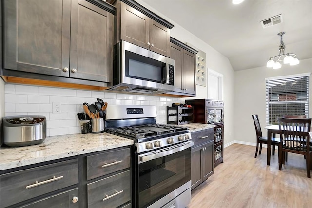 kitchen with light wood finished floors, stainless steel appliances, tasteful backsplash, hanging light fixtures, and dark brown cabinetry