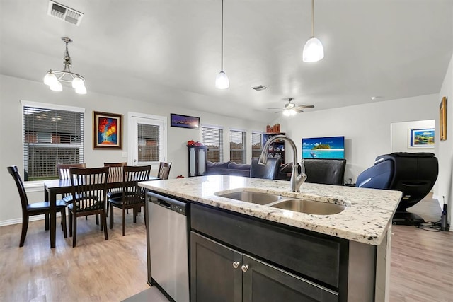 kitchen with a sink, open floor plan, hanging light fixtures, dishwasher, and a center island with sink