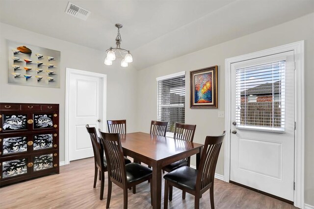 dining room with a chandelier, light wood finished floors, visible vents, and baseboards