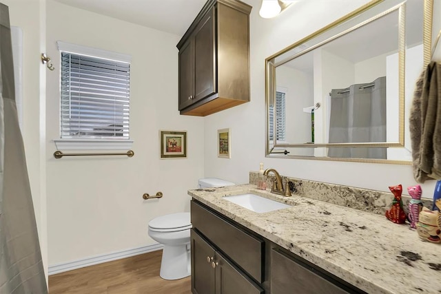 full bathroom featuring toilet, wood finished floors, vanity, and baseboards