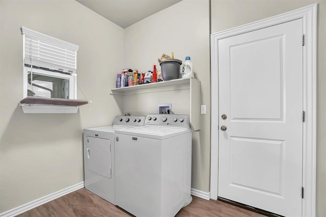 clothes washing area featuring laundry area, separate washer and dryer, wood finished floors, and baseboards