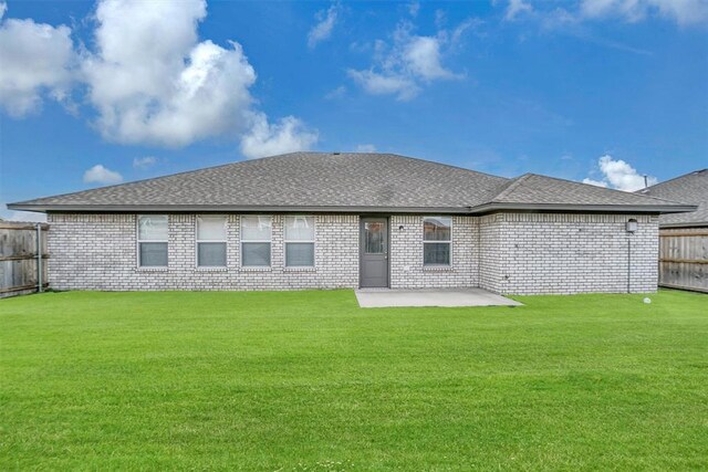 rear view of property featuring a patio, a fenced backyard, roof with shingles, a yard, and brick siding