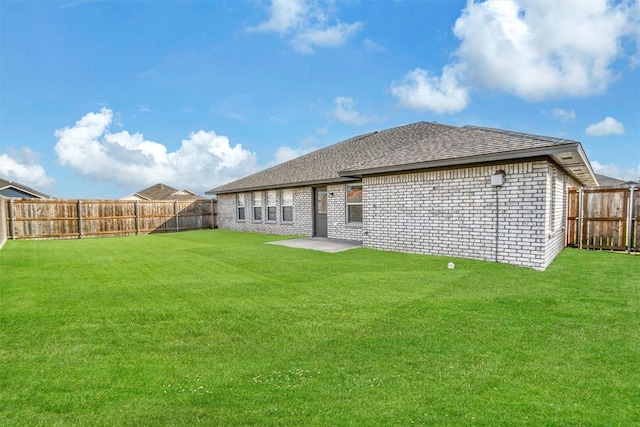 back of house featuring a fenced backyard, a lawn, and brick siding