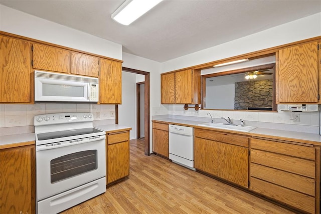 kitchen with tasteful backsplash, sink, light hardwood / wood-style floors, and white appliances