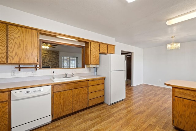 kitchen with white appliances, ceiling fan with notable chandelier, sink, hanging light fixtures, and light hardwood / wood-style floors