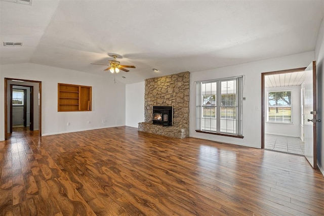 unfurnished living room with a wood stove, ceiling fan, vaulted ceiling, and hardwood / wood-style flooring