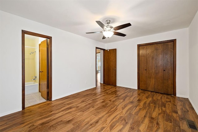 unfurnished bedroom with ceiling fan, a closet, dark hardwood / wood-style flooring, and ensuite bath