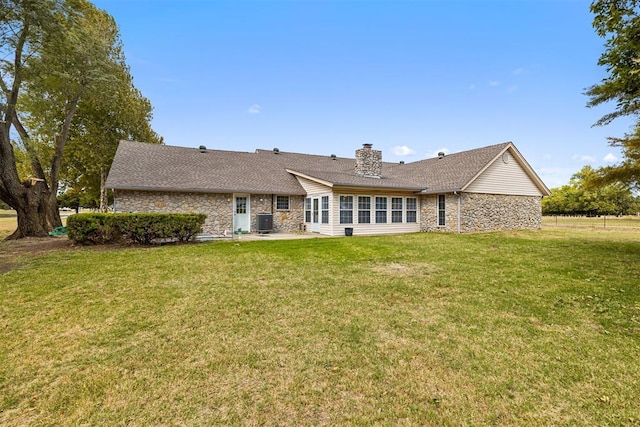 back of property featuring a lawn and central air condition unit