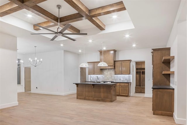 kitchen featuring light hardwood / wood-style flooring, hanging light fixtures, backsplash, coffered ceiling, and an island with sink