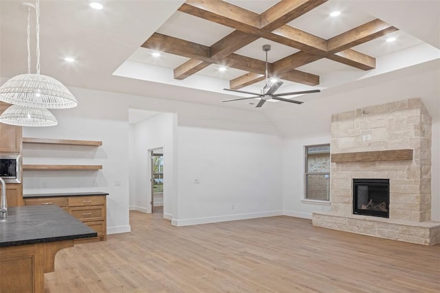 living room featuring a fireplace, coffered ceiling, ceiling fan, beam ceiling, and light hardwood / wood-style flooring