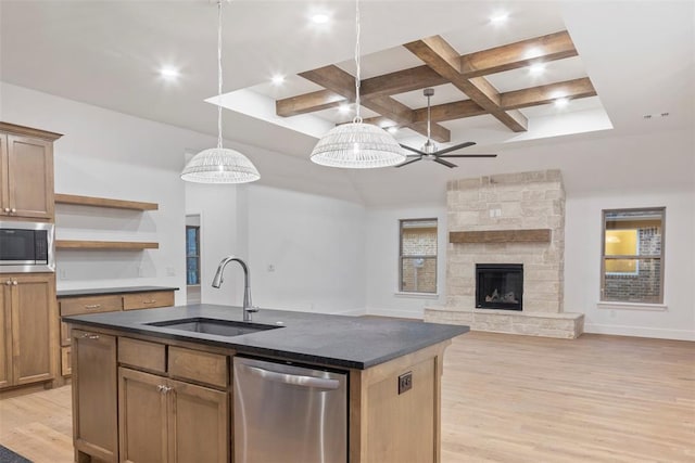 kitchen featuring appliances with stainless steel finishes, decorative light fixtures, an island with sink, sink, and light hardwood / wood-style floors