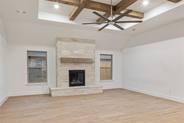 unfurnished living room with beamed ceiling, ceiling fan, a fireplace, and light wood-type flooring