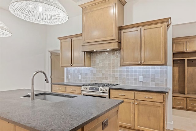 kitchen with sink, a kitchen island with sink, backsplash, decorative light fixtures, and stainless steel range with gas cooktop