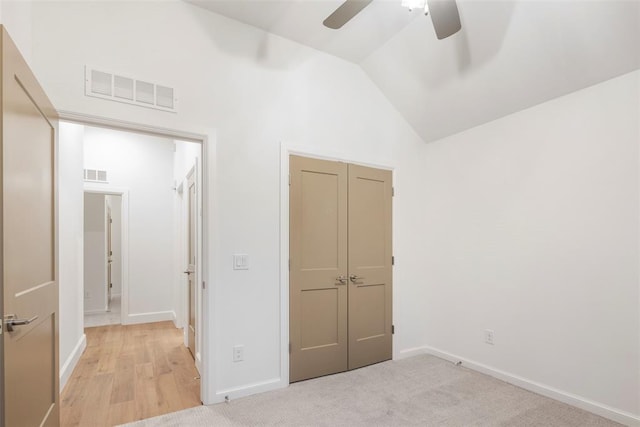 unfurnished bedroom featuring high vaulted ceiling, light colored carpet, ceiling fan, and a closet