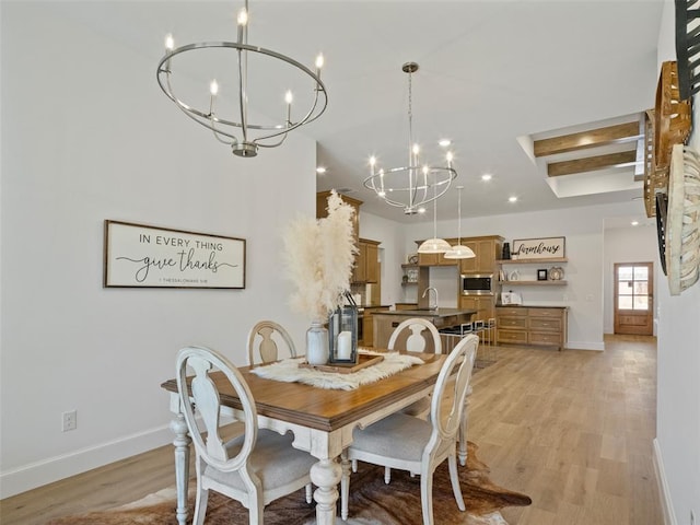 dining area with sink, a notable chandelier, and light hardwood / wood-style floors