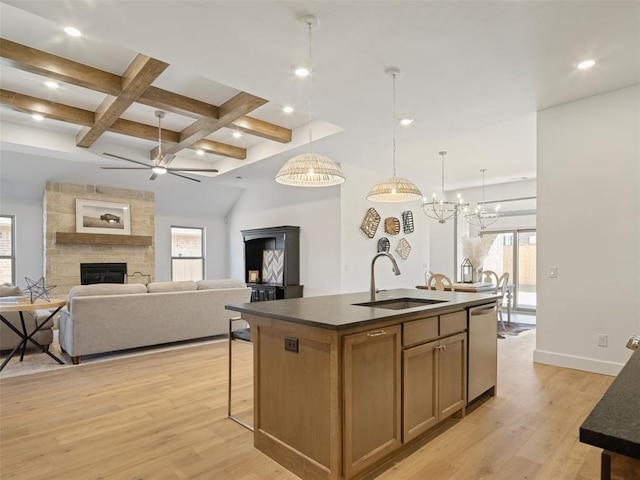 kitchen with pendant lighting, an island with sink, sink, stainless steel dishwasher, and light hardwood / wood-style flooring