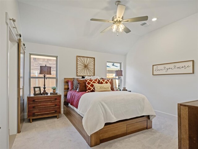 bedroom with a barn door, light colored carpet, lofted ceiling, and ceiling fan