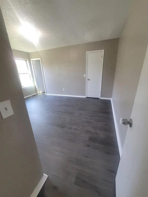 unfurnished room with dark hardwood / wood-style flooring and a textured ceiling