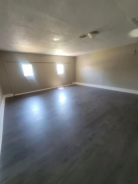 spare room with dark hardwood / wood-style flooring and a textured ceiling