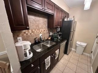 kitchen with dark brown cabinetry, sink, decorative backsplash, light tile patterned floors, and appliances with stainless steel finishes