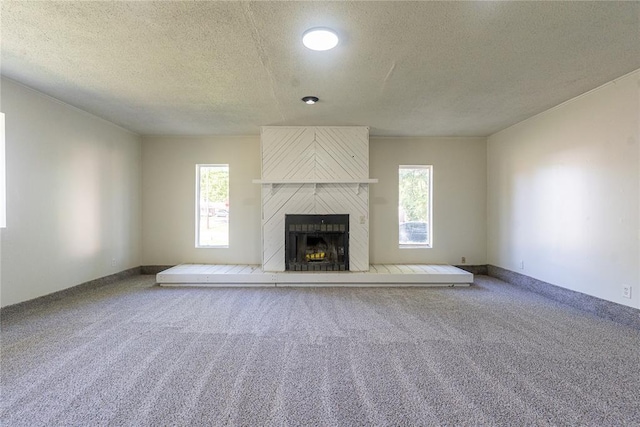 3201 Longridge Rd, Del City, OK 73115 - unfurnished living room with carpet flooring, a large fireplace, a textured ceiling, and plenty of natural light