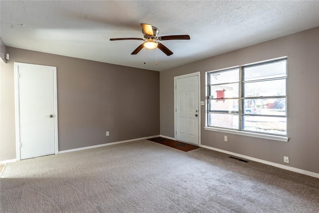 carpeted spare room featuring ceiling fan and a textured ceiling