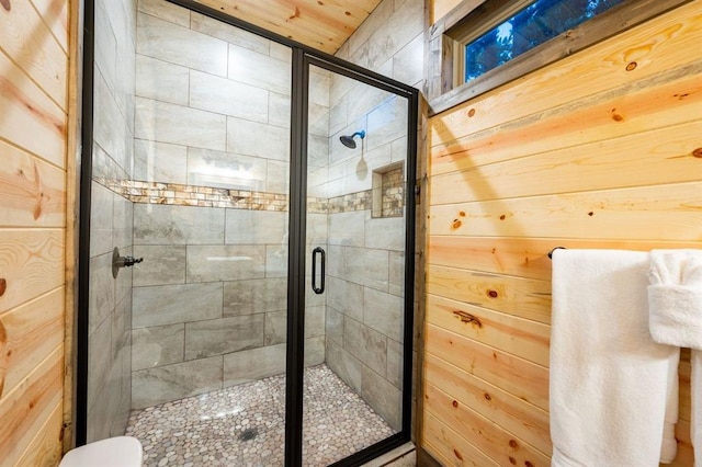 bathroom featuring toilet, wood walls, and a shower with door